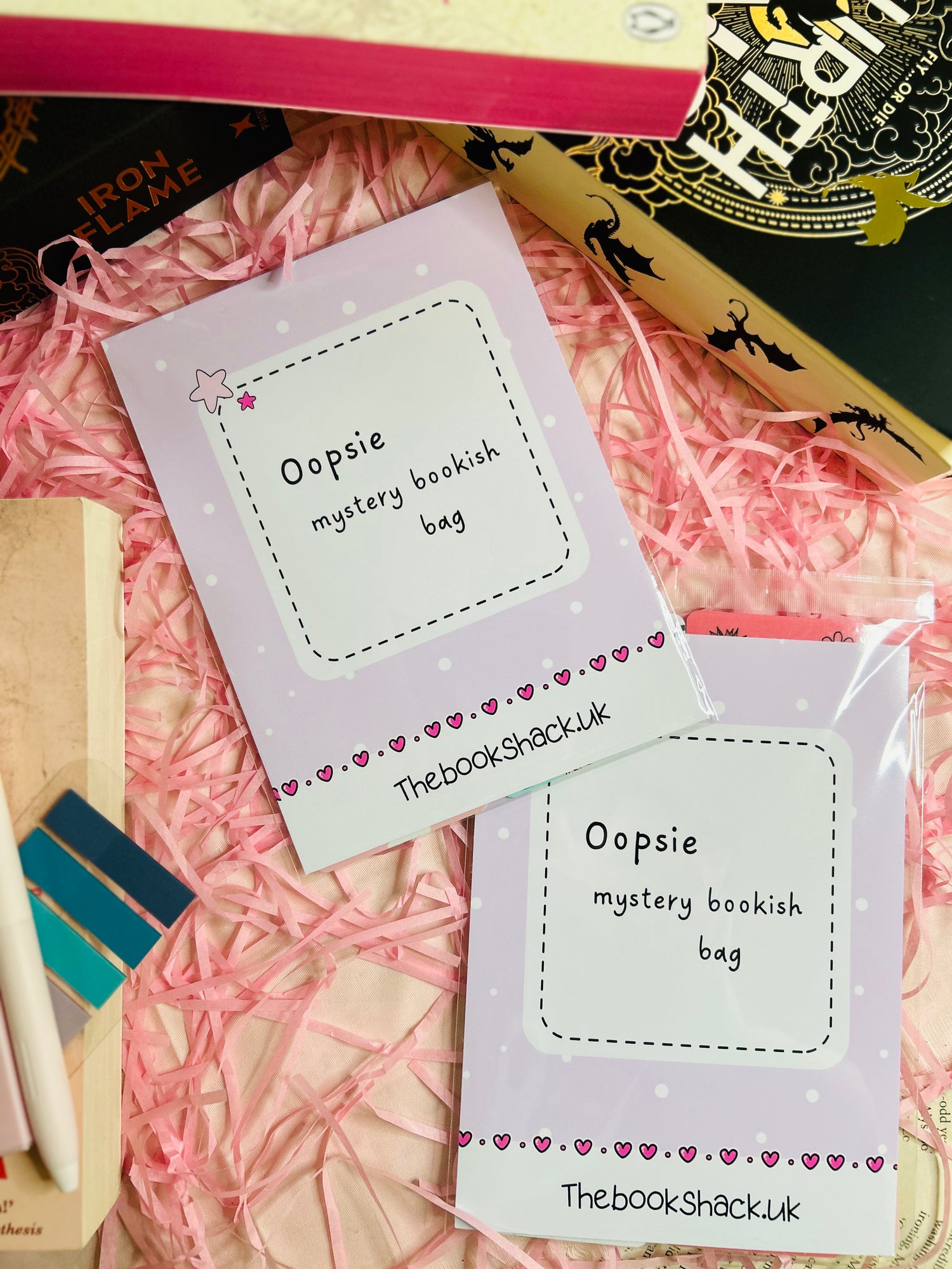 A colourful display of our Oopsie Mystery Grab Bag contents, featuring five unique bookish items such as bookmarks and stickers with minor imperfections.