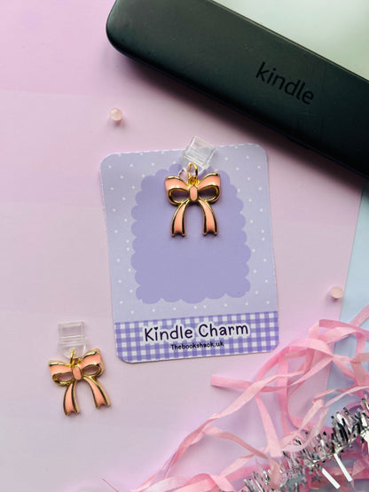 Pink bow Kindle charm attached to a clear plastic Type-C dust plug, displayed with backing card and holographic packaging, shown with optional white letter charm.
