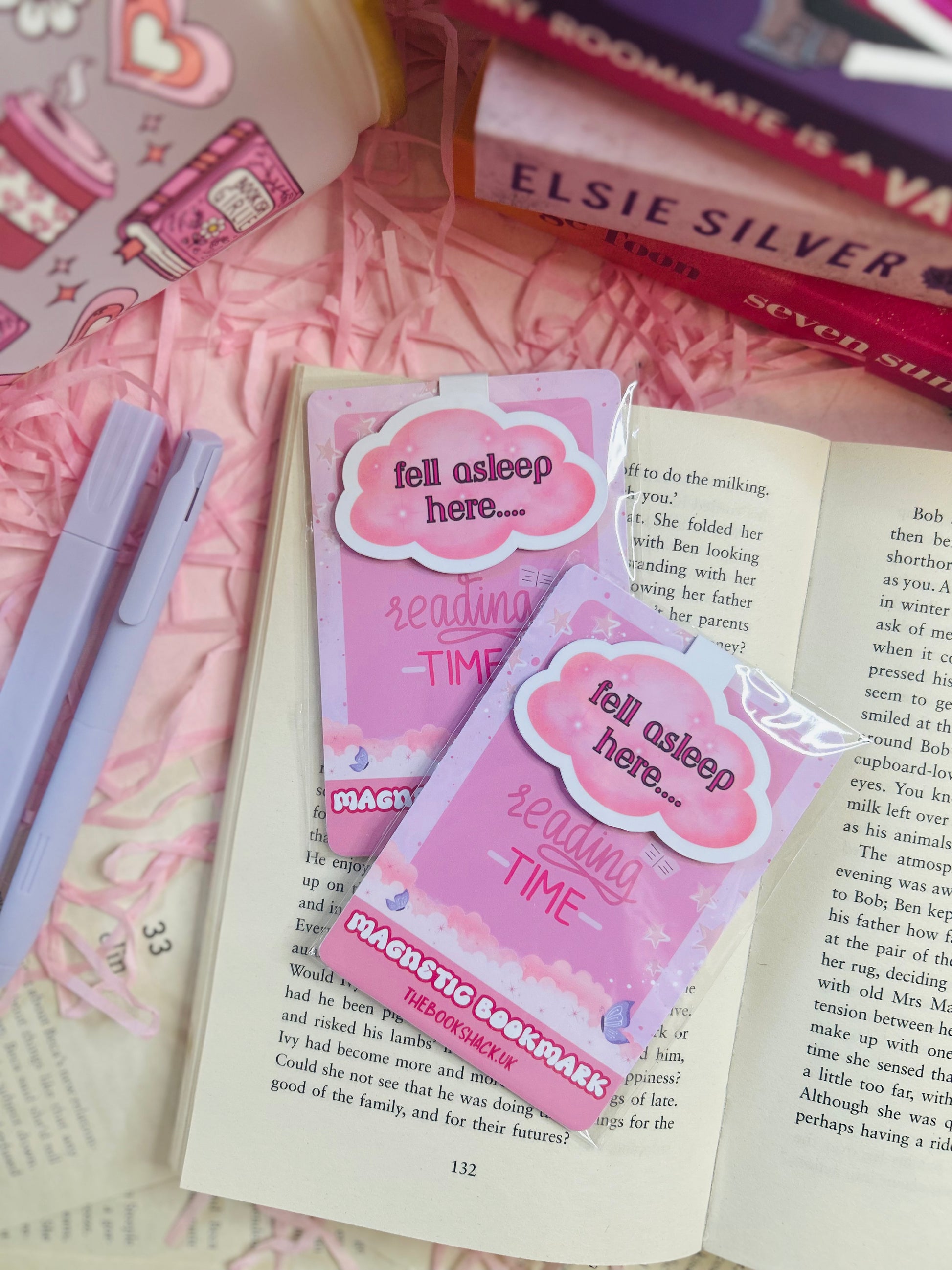 Cloud-shaped magnetic bookmark with the phrase ‘Fell Asleep Here...’ on soft pastel packaging, styled on an open book with cosy pink surroundings.