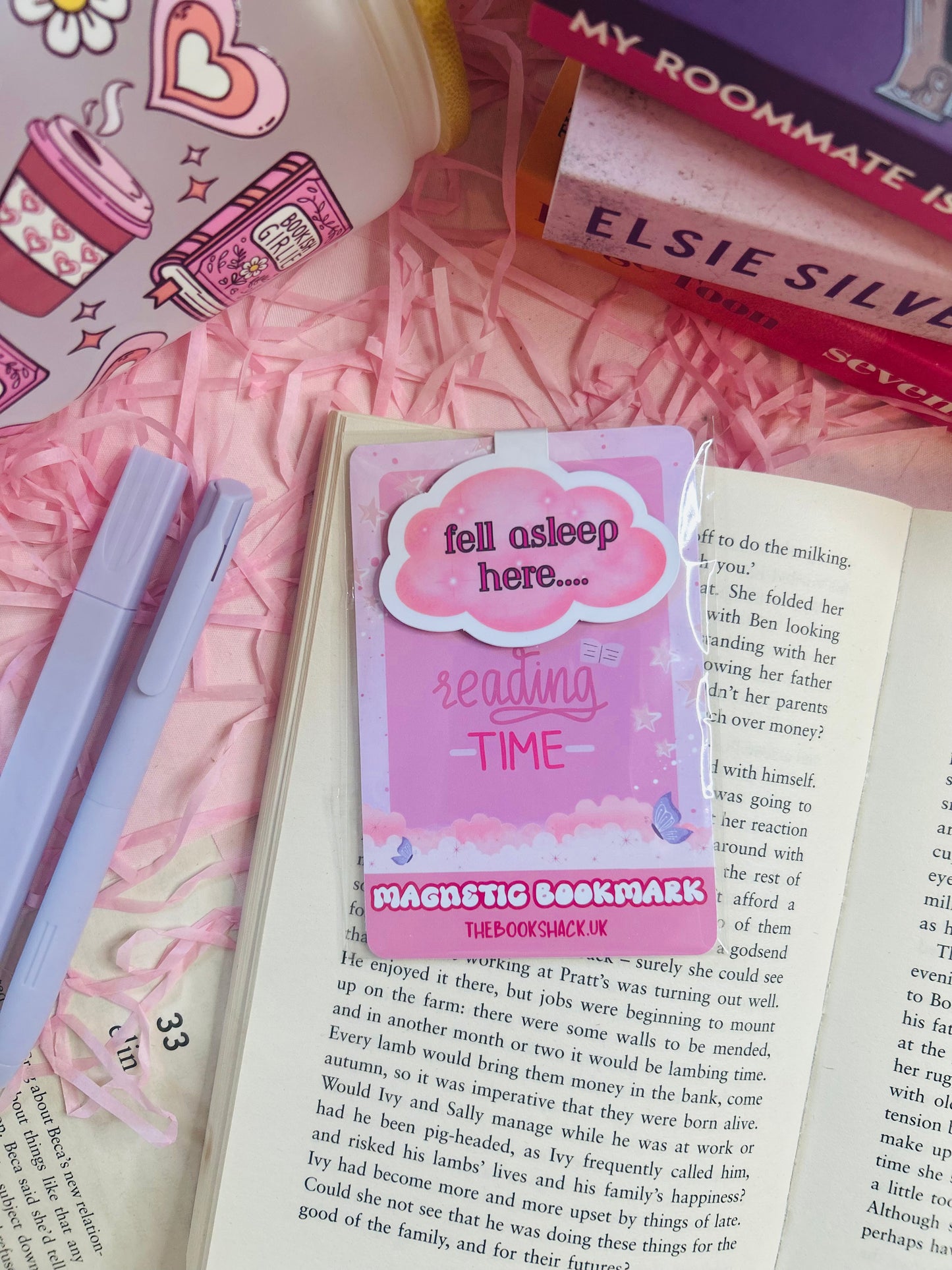 Cloud-shaped magnetic bookmark with the phrase ‘Fell Asleep Here...’ on soft pastel packaging, styled on an open book with cosy pink surroundings.