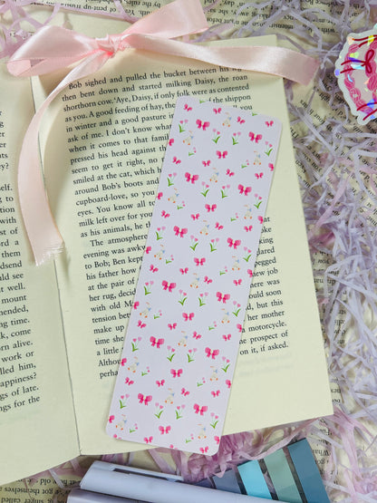 Set of three pastel bookmarks with silly goose and bow designs, placed on an open book with soft pink ribbon, shredded filler, and pens.