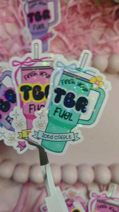 Pastel iced coffee bookish vinyl stickers with "Finish Your TBR Fuel" text, surrounded by pink shredded paper and decorative beads – perfect for readers and book lovers.