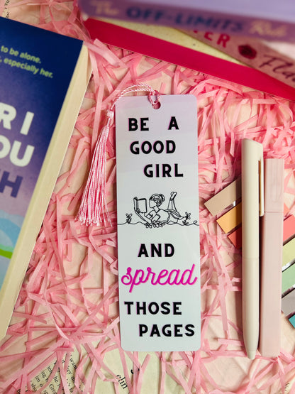 Aesthetic tassel bookmark with the quote 'Be a Good Girl and Spread Those Pages' placed on a romance book
