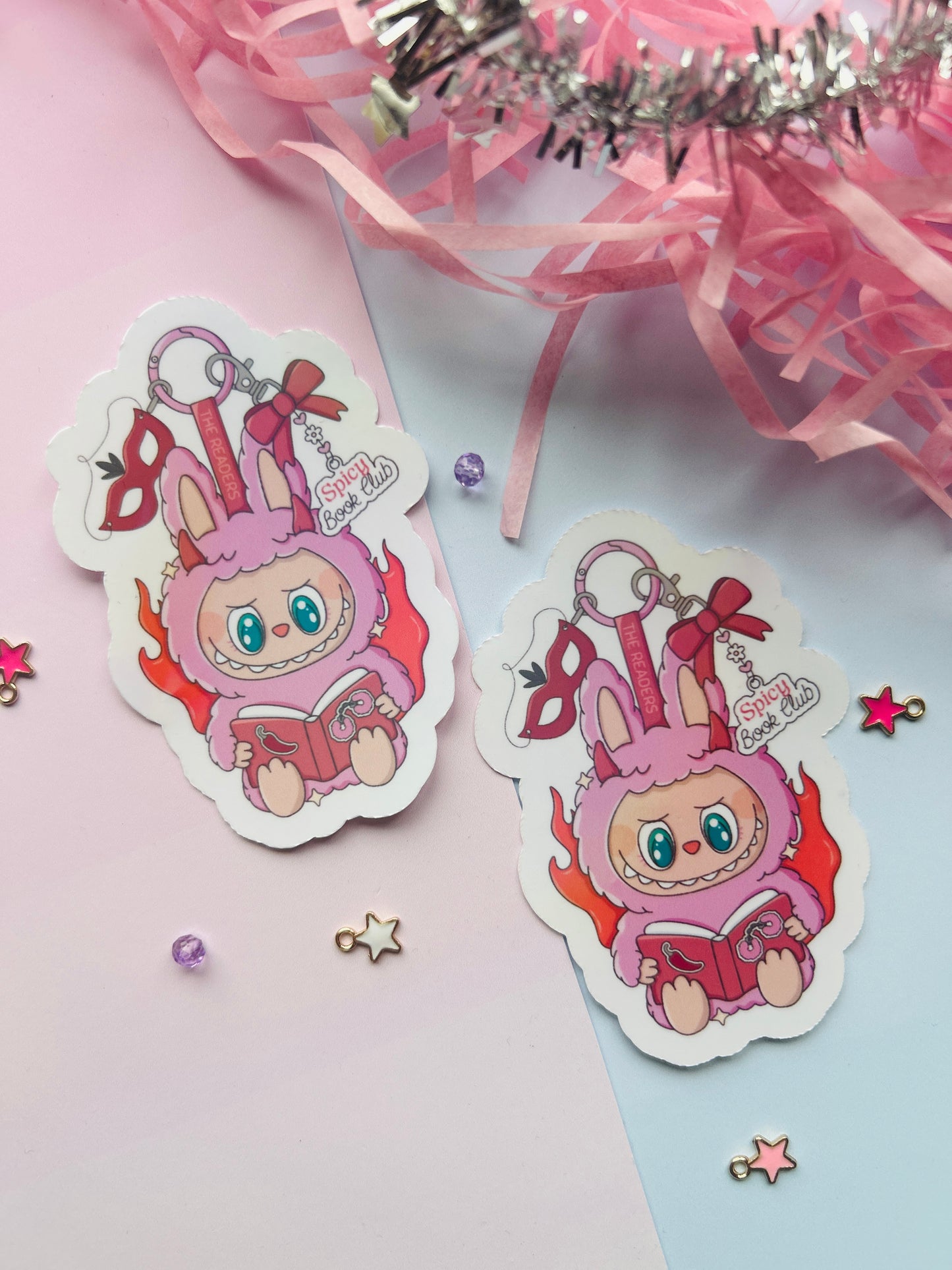 Two pink character stickers with ribbons on a light pink background