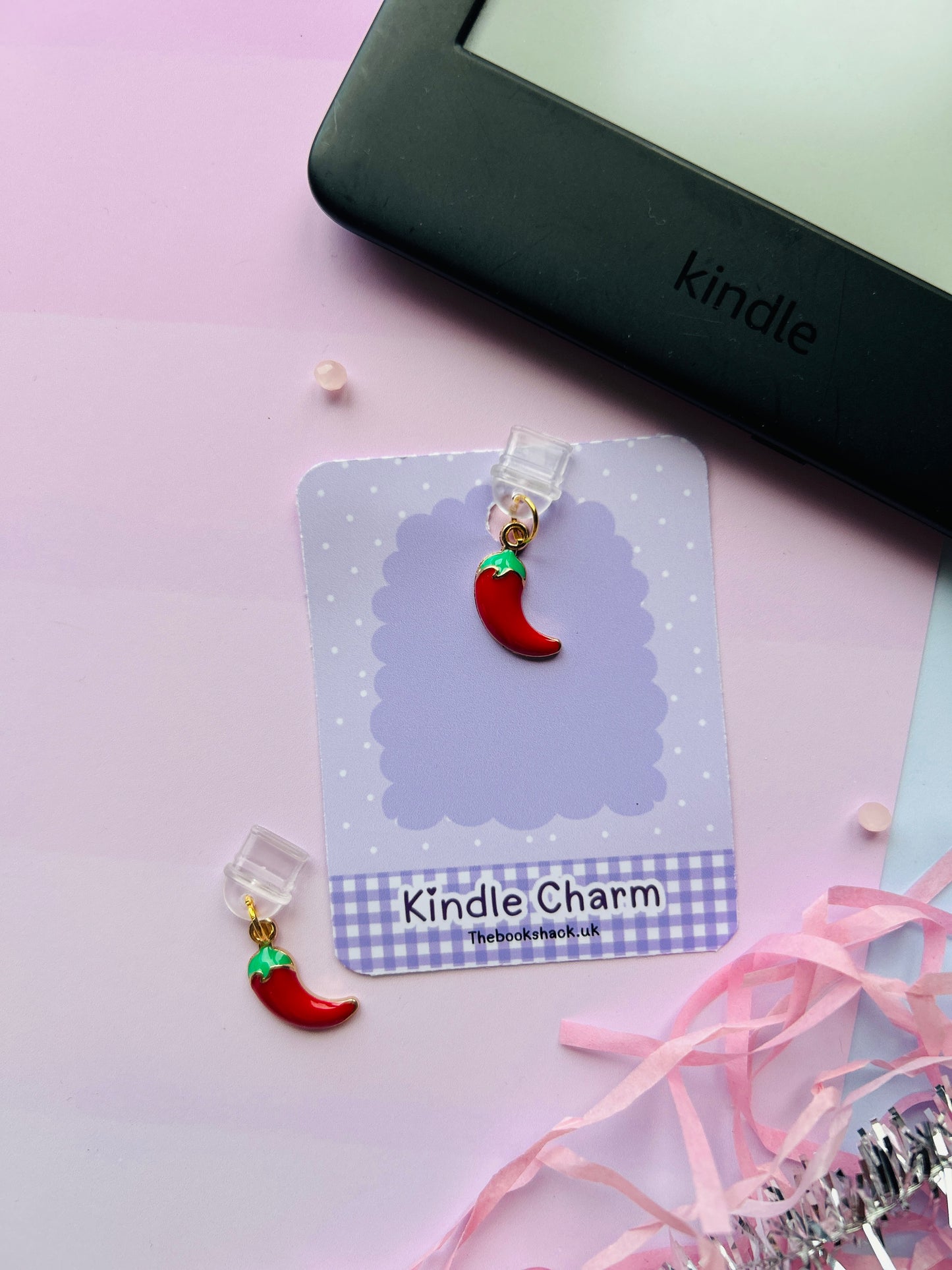 Spicy chilli Kindle charm attached to a clear plastic Type-C dust plug, shown with backing card and holographic packaging, with optional white letter charm.