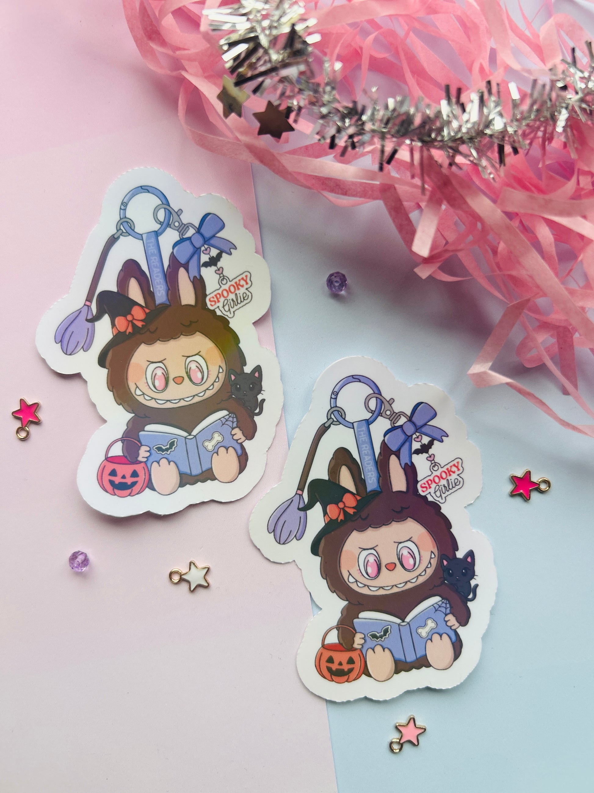 Two identical stickers of a cartoon character with bunny ears on a pink background with decorative elements.