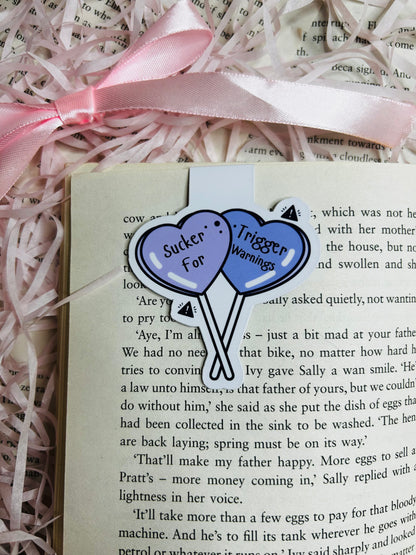 Magnetic bookmark featuring two soft purple heart-shaped balloons inscribed with 'Sucker for Trigger Warnings.'
