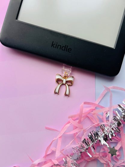 white bow Kindle charm attached to a clear plastic Type-C dust plug, displayed with backing card and holographic packaging, shown with optional white letter charm.